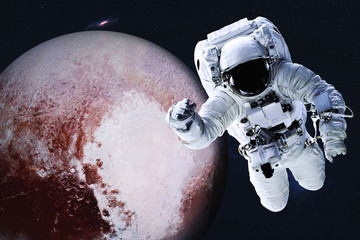 Obraz na płótnie Canvas Astronaut near Planet Pluto of Solar system in space with far galaxy on the background. Science fiction. Spaccewalk concept. Elements of this image were furnished by NASA 