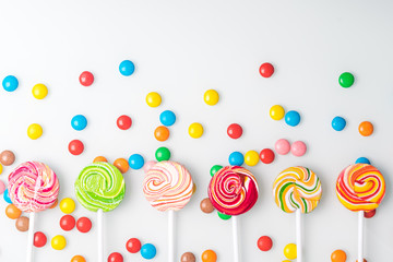 multi-colored chocolate tablets and caramel candies on a stick lie beautifully on a light...