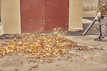 municipal worker removes fallen autumn fallen leaves