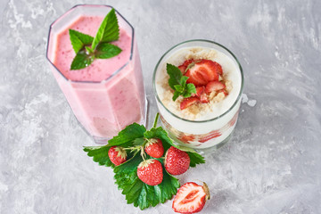 Strawberry smoothie in glass jar and fresh strawberries on a gray background
