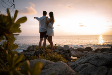 Couple amoureux sur une plage au bord de l'eau au coucher de soleil