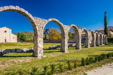 Fototapeta na wymiar San Vincenzo al Volturno, a Benedictine monastery in Castel San Vincenzo and Rocchetta a Volturno. The new abbey. The remains of walls of an ancient building, with a series of stone arches.