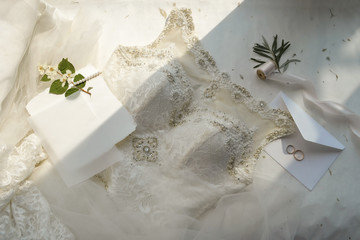 Wedding dress, veil, envelope, invitation card, ribbon, golden rings on soft beige flat lay mock up