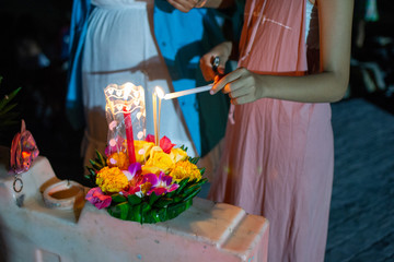 Authentic celebration of Loi Krathong in Thailand flower boats customs, girl lights a candle