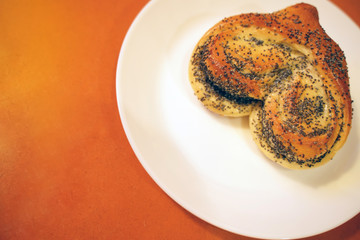 Valentine bun for breakfast for lovers on orange table background
