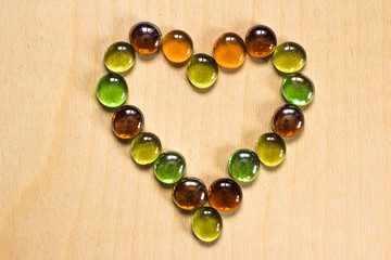 The heart is lined with glass stones on a wooden background. Colorful lollipops on a wooden tableмммммThe heart is lined with glass stones on a wooden background. Colorful lollipops on a wooden table