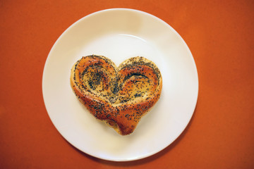 Valentine bun for breakfast for lovers on orange table background