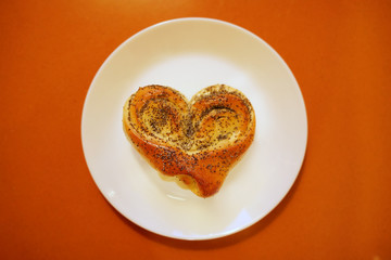 Valentine bun for breakfast for lovers on orange table background