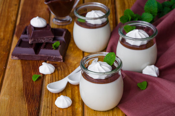 Traditional Italian dessert panna cotta with chocolate sauce and crispy meringue, dessert for Valentine's Day served in glass jars.