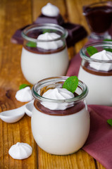 Traditional Italian dessert panna cotta with chocolate sauce and crispy meringue, dessert for Valentine's Day served in glass jars.