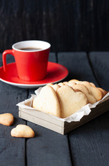 Red cup and cookie hearts on a black background..