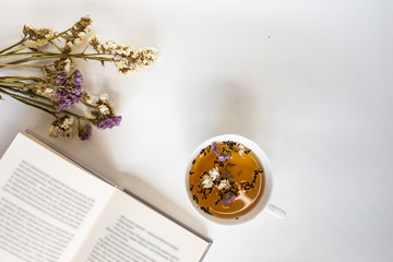 Tea, flowers and book on a white background. Morning billet for the designer.
