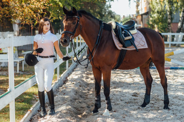 Young woman in special uniform and helmet with her riding horse. Equestrian sport dressage.