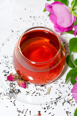 tea with wild rose in a glass cup on a white background, top view closeup