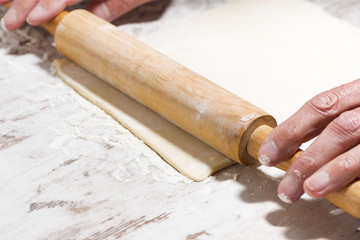 the process of rolling dough. hands and rolling pin, closeup