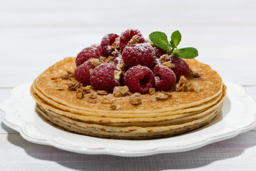 traditional thin pancakes with fresh raspberries on wooden table
