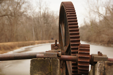 Rusted and misaligned gears in a non-functioning lock with the C&O Canal in the background - near...