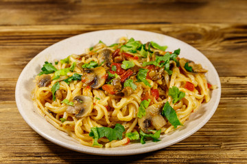 Pasta with mushrooms and tomato sauce on wooden table