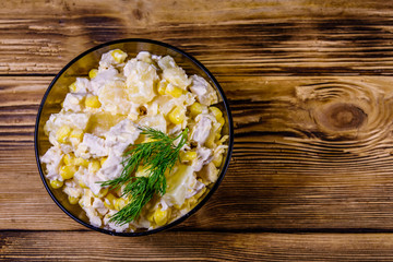 Obraz na płótnie Canvas Festive salad with chicken breast, canned pineapple, cheese, sweet corn and mayonnaise on wooden table. Top view