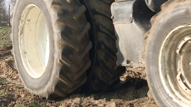 A plow, towed by a large eight tire tractor, is turning up a farm field in preparation for planting. Tractor plowing fields -preparing land for sowing 