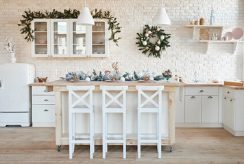 Interior light kitchen with christmas decor and tree. White kitchen in classic style. Christmas in the kitchen. Bright kitchen in white shades with Christmas.