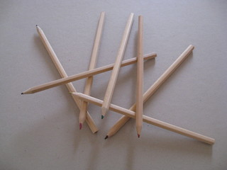 Lápices de minas de colores rosa, rojo, verde, amarillo, negro, azul,en madera natural descolocados sobre fondo de carpeta gris para dibujar