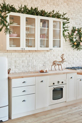 Interior light kitchen with christmas decor and tree. White kitchen in classic style. Christmas in the kitchen. Bright kitchen in white shades with Christmas.
