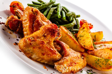 Fried chicken wings with baked potatoes and vegetable salad