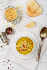 Minestrone. Chicken soup with potatoes, carrots and pasta Orzo in a white plate on a wooden table. Minestrone.  Mediterranean (Italian) cuisine. Selective focus