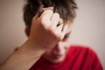A 18 year old teenager covers his face in despair with his hand