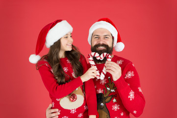 Share joy and happiness. Christmas Carol. Father and daughter with candy canes christmas decorations. Family holiday. Santa claus family look. Bearded dad and cheerful little girl. Christmas games