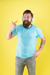 Play it loud. Bearded man point at headphones yellow background. Hipster listen to music in stereo headphones. Using modern wireless headphones. Headphones designed to deliver clean sound