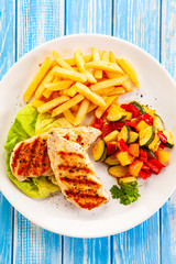 Grilled chicken breast with french fries and vegetables