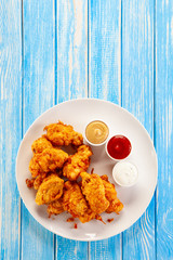 Chicken nuggets with sauces on white plate