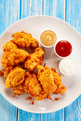 Chicken nuggets with sauces on white plate