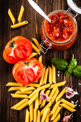 Raw tomatoes,uncooked pasta and tomato sauce in jar