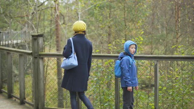 Zoological garden and amusement park of Kristiansand - young woman and her son are walking along wooden walking path