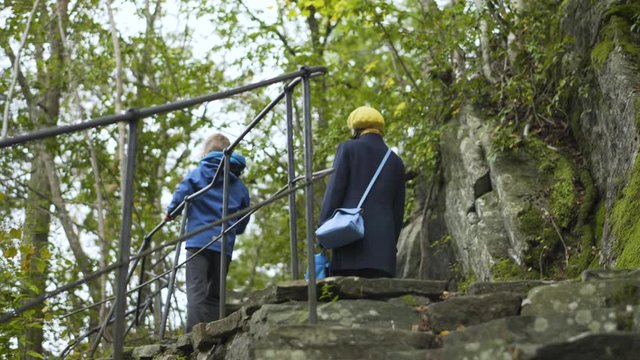 Zoological garden and amusement park of Kristiansand - young woman and her son are walking along walking path uphill