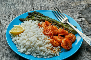 Grilled shrimps and asparagus with rice and sesame on a rustic table. Seafood meal dinner. Close-up shot.