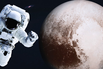 Astronaut near Planet Pluto of Solar system in space with far galaxy on the background. Science fiction. Spaccewalk concept. Elements of this image were furnished by NASA  - obrazy, fototapety, plakaty