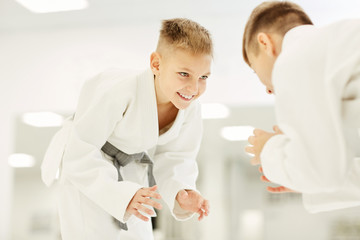 Little karateka smiling to his rival during their fight on competition in karate