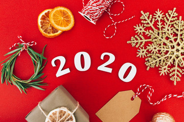 Wooden 2020 numbers and Christmas decorations on red background. Holiday zero waste concept.