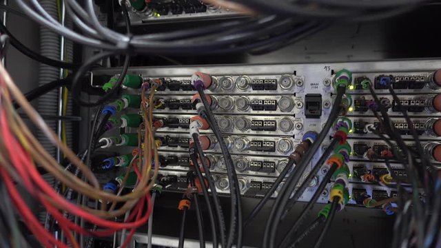 Back commutation panel of telecommunication video switcher with lot of jacks in broadcast technical room of TV channel. The video has vibrations. Handheld shooting without stabilization