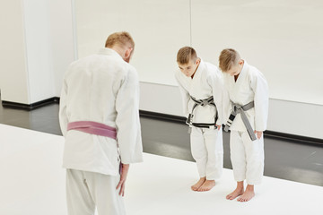 Obraz premium Coach in kimono tanding and greeting his students before lesson in the gym