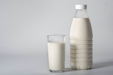 Glass of milk and a bottle on a gray background. Dairy products