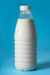 A plastic bottle of milk, on a blue background. Close-up.