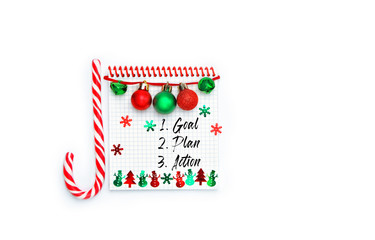 new year goal, plan, action - text on notepad and festive winter decor. Business motivation, inspiration concept. notebook, decor, candy cane on white background. New year holiday concept. 