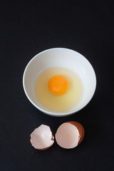 YOLK IN BOWL AND SHELLS ON BLACK BACKGROUND