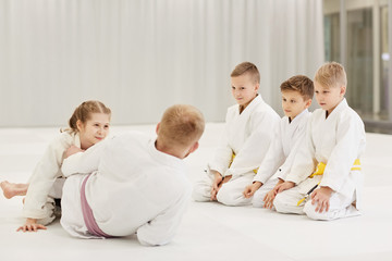 Coach teaching the group of children they practicing in karate on the floor in the gym