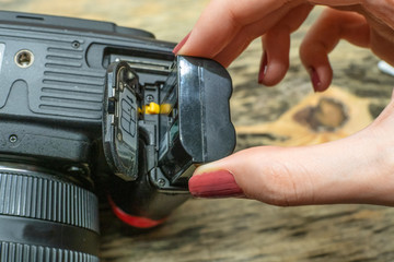 A photographer changes the battery in his SLR camera while shooting in the Studio. focus on the...